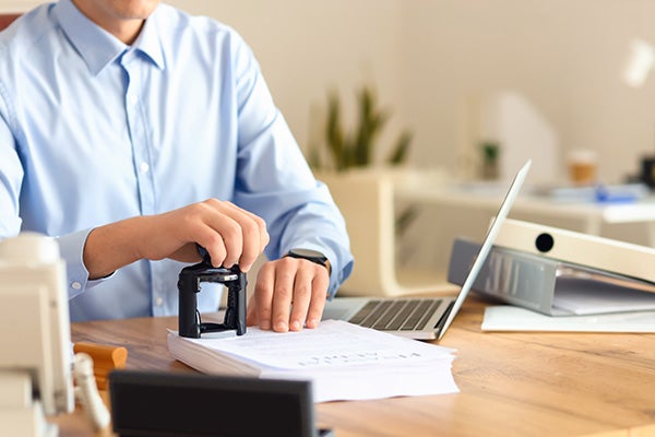 notary public attaching seal to documents in office