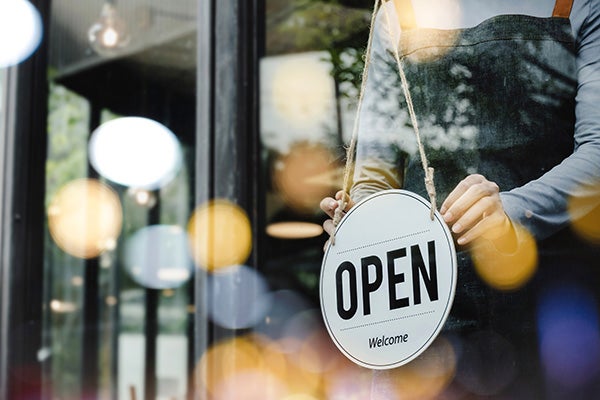 Women putting out an open sign at her business