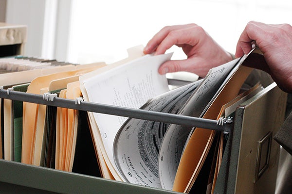 hands filing through folders in a filing cabinet