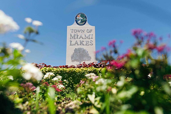 The town sign for Miami Lakes surrounded by foliage